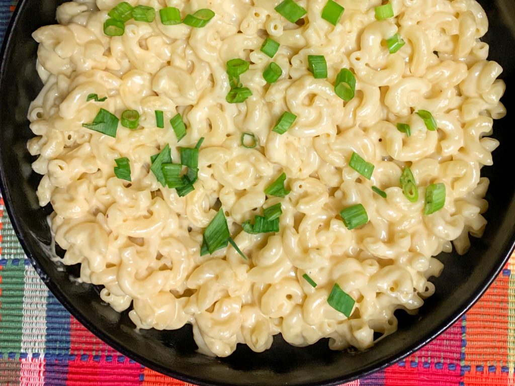 Bowl of creamy elbow mac and cheese in a Parmesan cheddar sauce, topped with chopped green onions.